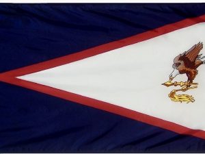 A photo of the American Samoa flag, featuring a red-bordered white triangle with a blue eagle holding a fly-whisk and war club in its talons, all on a blue field.