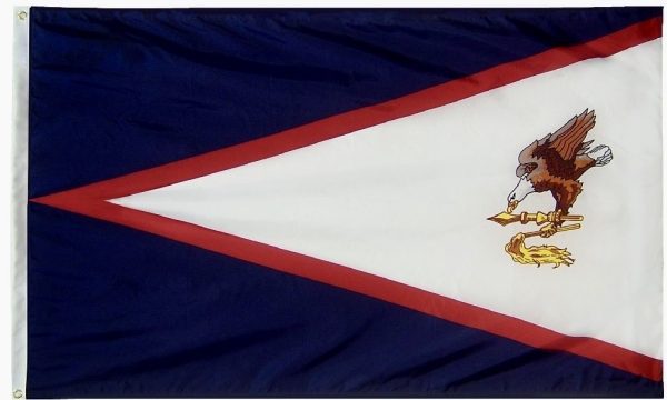 A photo of the American Samoa flag, featuring a red-bordered white triangle with a blue eagle holding a fly-whisk and war club in its talons, all on a blue field.